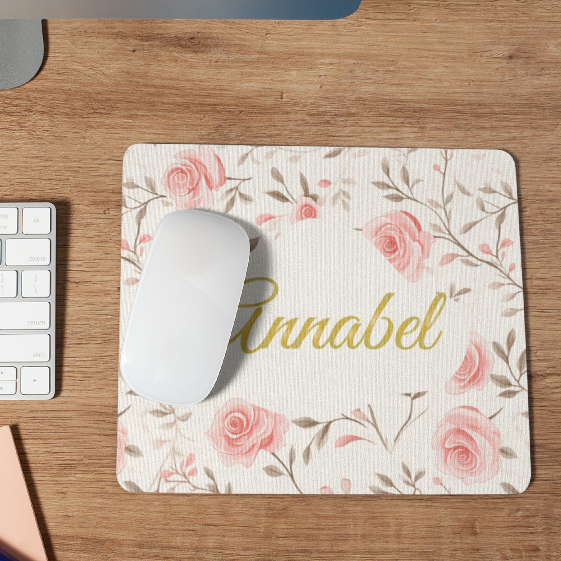 Muismat met roze rozen en een naam in sierlijk goud. De naam is aanpasbaar op een bureau met een witte muis erop 