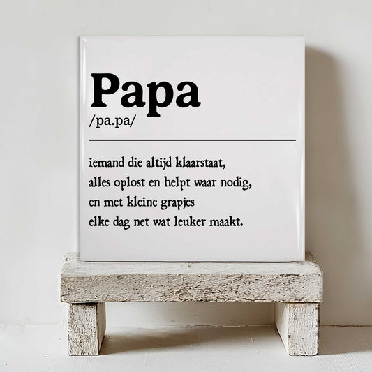 Minimalistisch keramisch papa tegeltje met zwarte typografie geplaatst op een klein wit houten krukje tegen een lichte muur