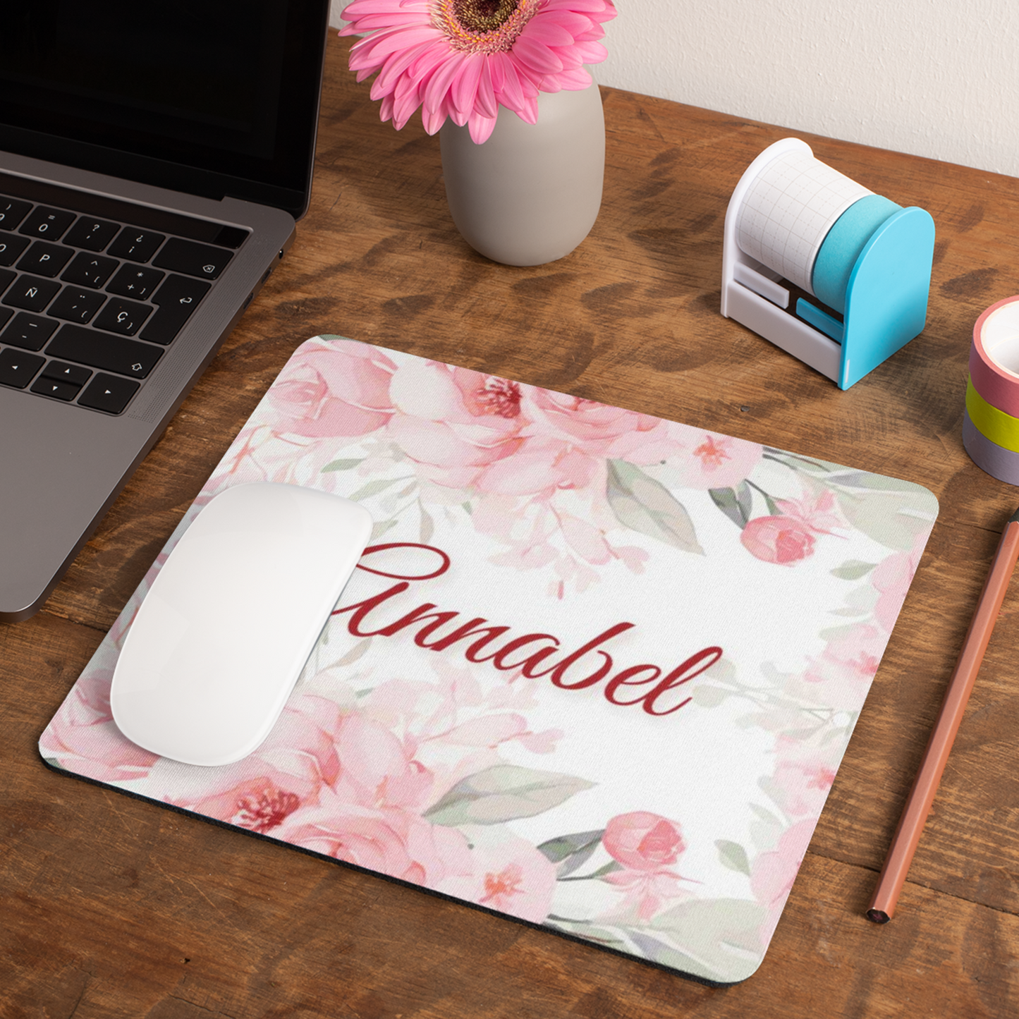 Muismat 22×19 cm met roze bloemen en naam Annabel, witte muis erop, gefotografeerd op houten bureau met laptop en roze bloem