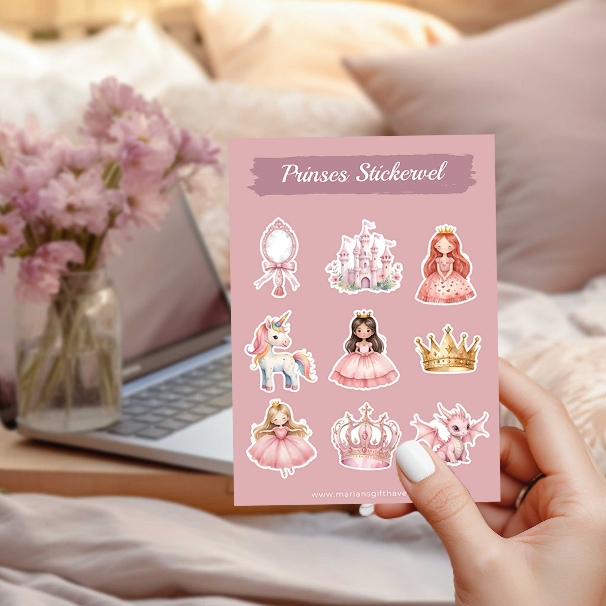 Hand die een prinsessenstickervel vasthoudt voor een laptop met bloemen op de achtergrond.