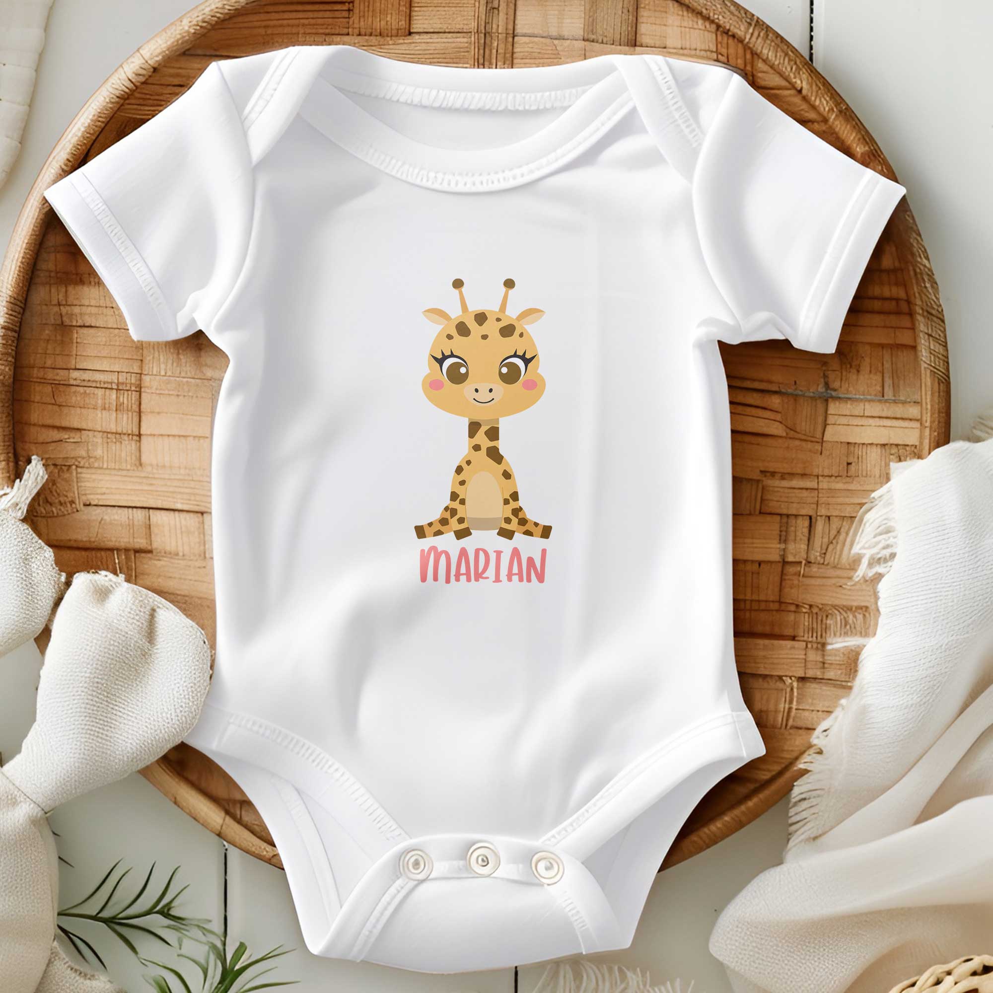 Witte babyromper met vrolijk girafje en naam gepresenteerd op mandje