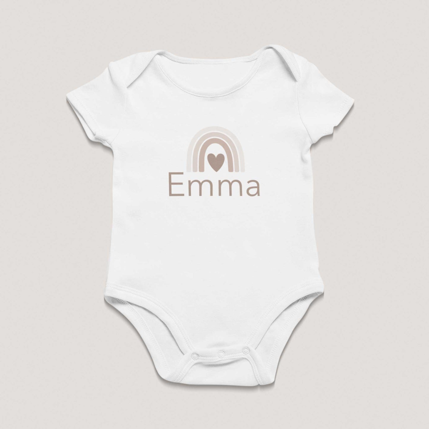Wit babyrompertje met korte mouwen en drukknoopjes onderaan, bedrukt met een beige regenboog met hartje en de naam Emma op een lichte neutrale achtergrond