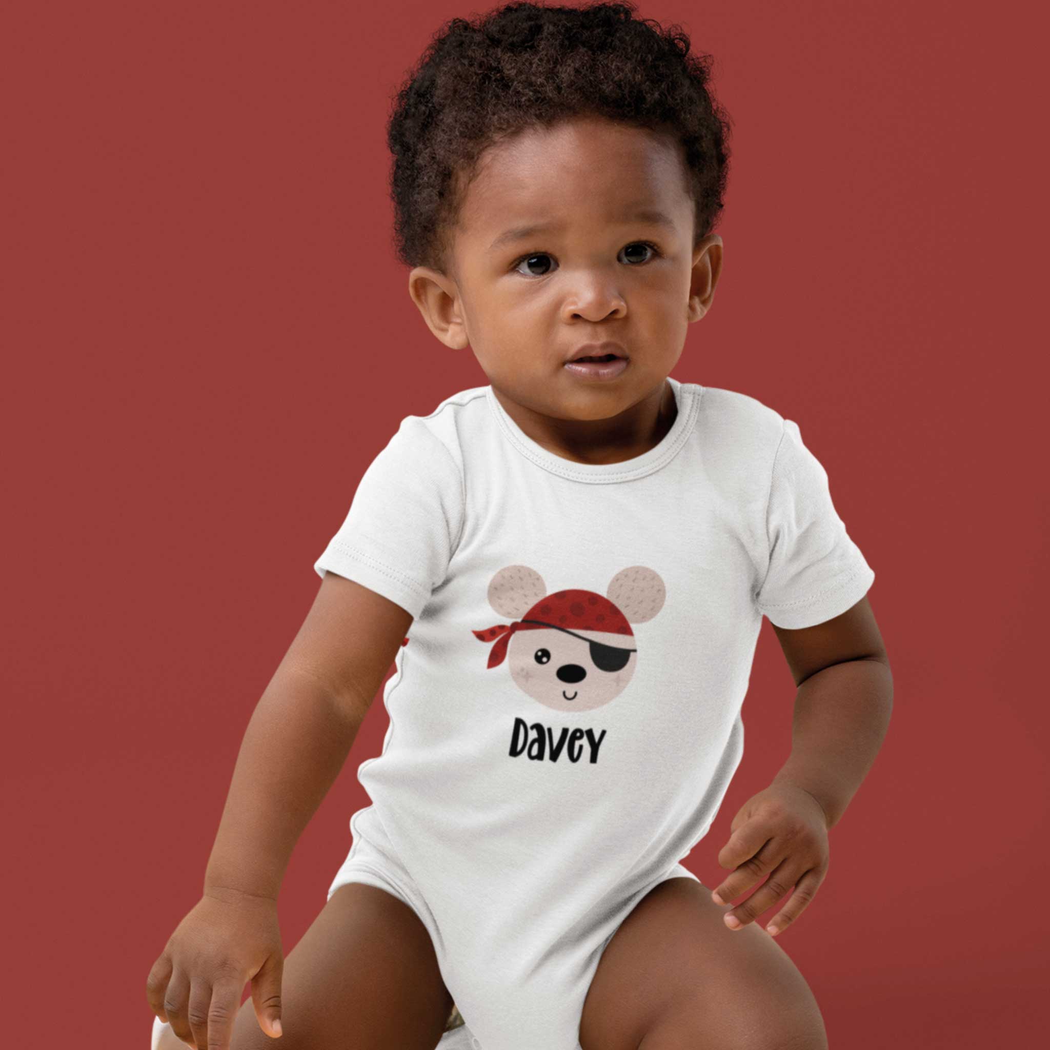 Babyrompertje wit met piratenprint en naam Davey, gedragen door baby