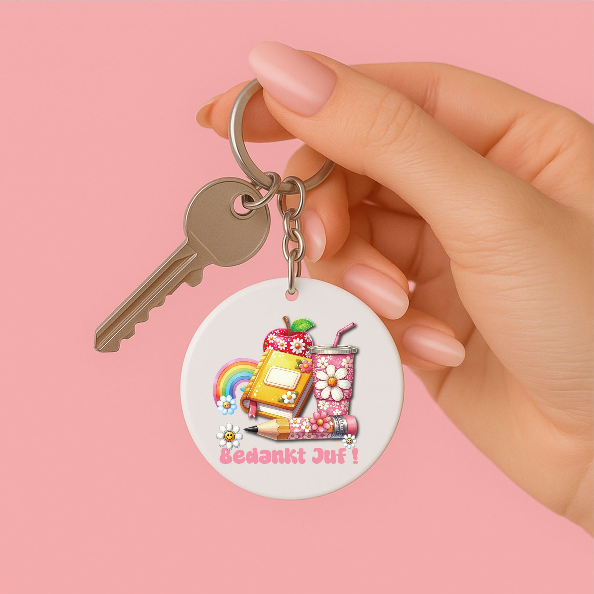 ronde sleutelhanger voor juf met de tekst bedankt juf in roze en groovy illustraties zoals een appel, boek, regenboog en beker met bloemen