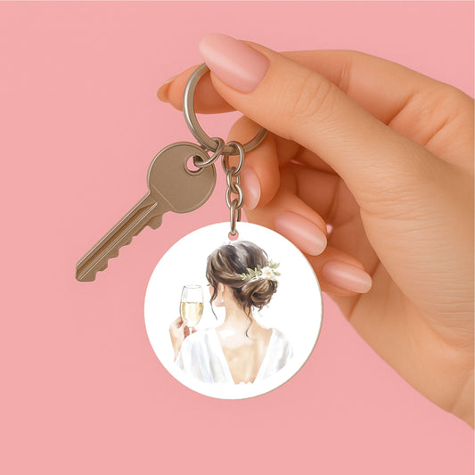 vrouwen hand met Ronde sleutelhanger met bruid in wit en champagneglas – elegant cadeau voor haar