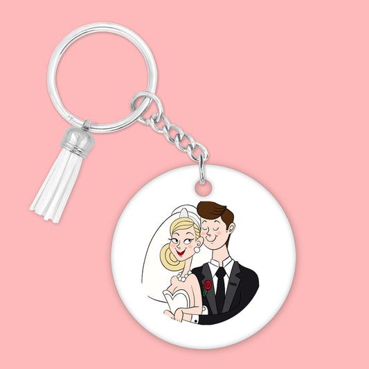 ronde witte sleutelhanger met een grappige cartoon van een bruidspaar