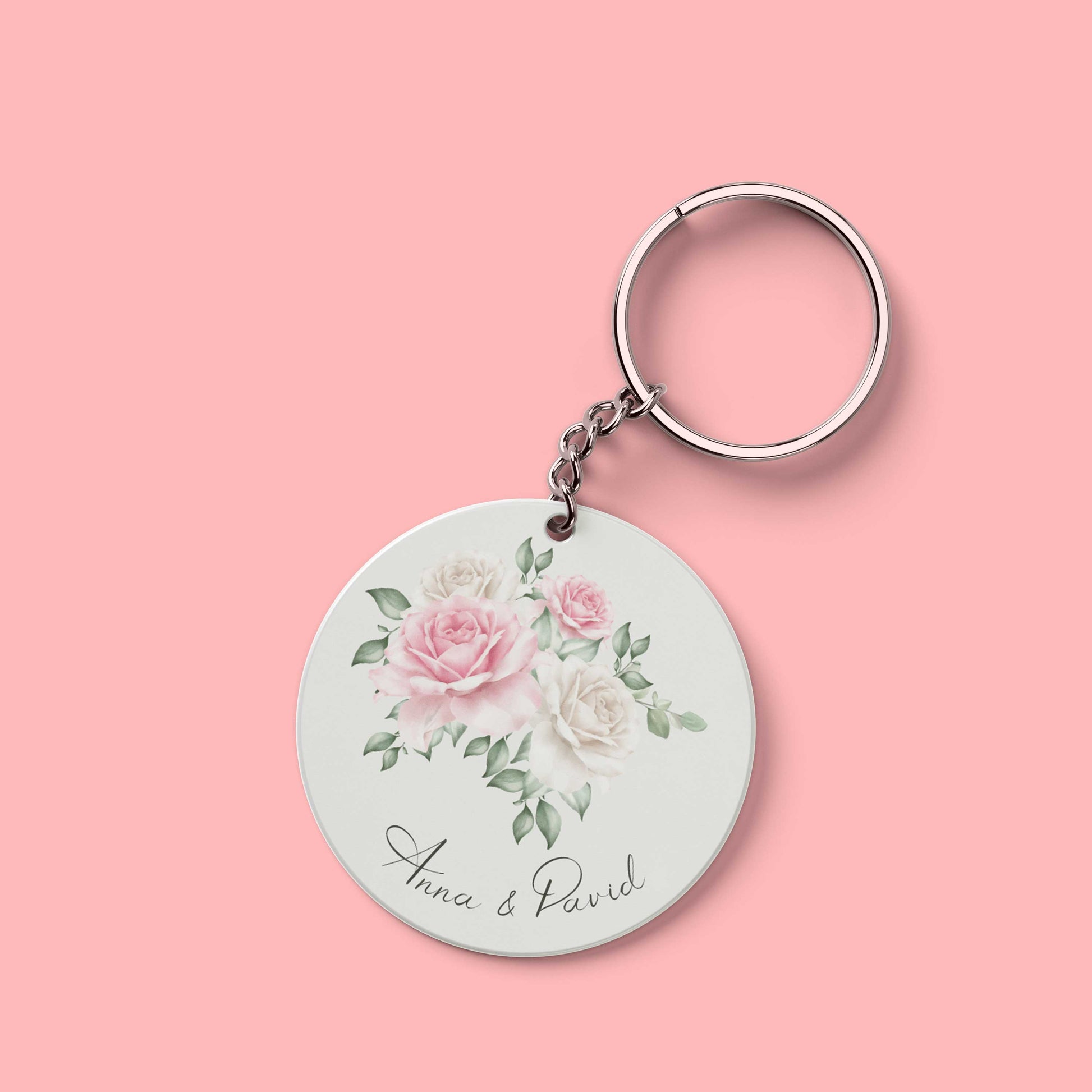 Ronde sleutelhanger met namen Anna & David en aquarelillustratie van roze en witte rozen op roze achtergrond