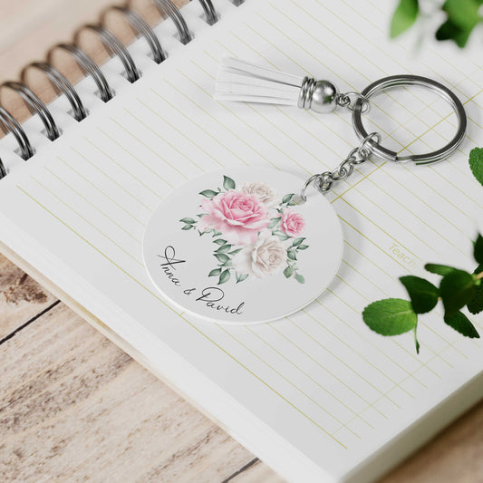Gepersonaliseerde sleutelhanger met rozenillustratie en namen Anna & David, met wit suède kwastje op notitieboek
