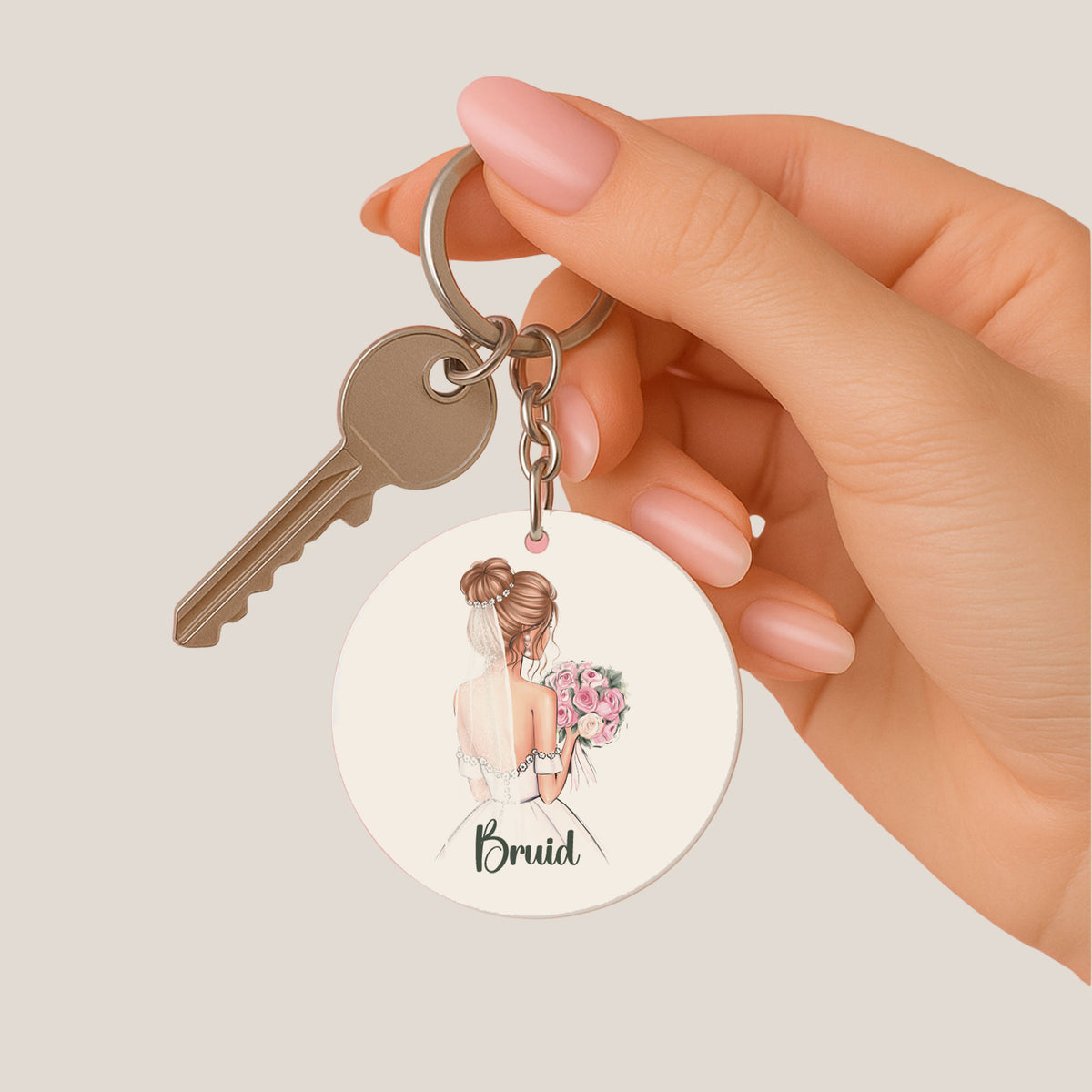 Ronde bruid sleutelhanger met roze boeket en witte kwast aan sleutelbos in hand