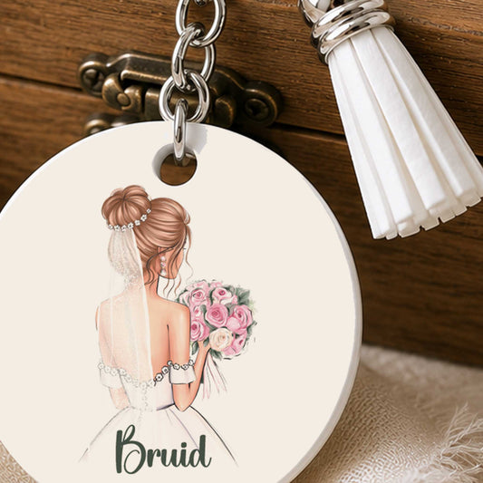 Close-up van ronde sleutelhanger met bruid, roze bruidsboeket en witte kwast