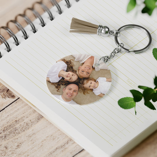 Gepersonaliseerde foto sleutelhanger met familiefoto en beige kwastje op notitieboek