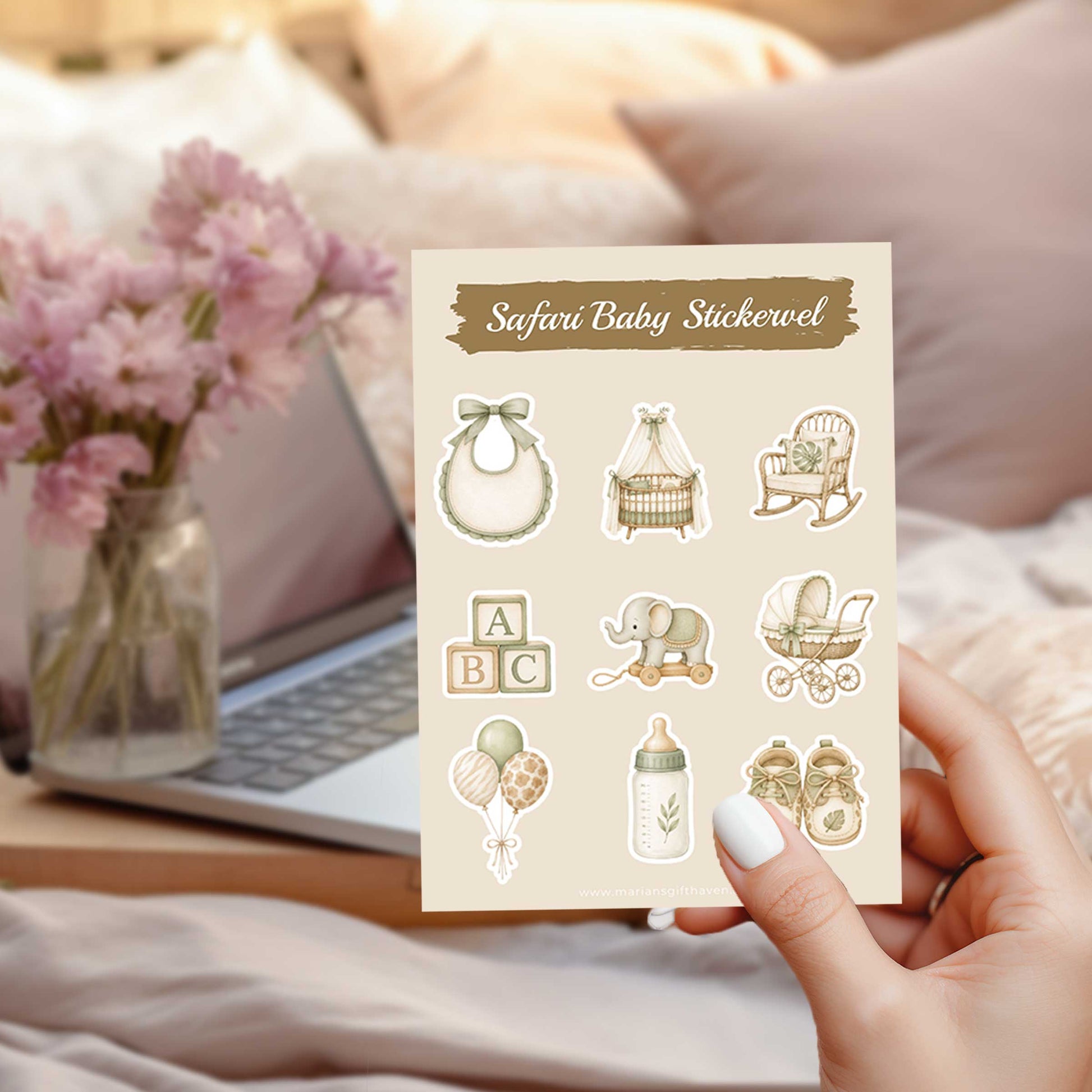 Safari baby stickervel met illustraties van een slabbetje, wiegje, schommelstoel, houten blokken, olifantje, kinderwagen, ballonnen, flesje en babyschoentjes in zachte neutrale kleuren, vastgehouden voor een laptop en roze bloemen op een bed.