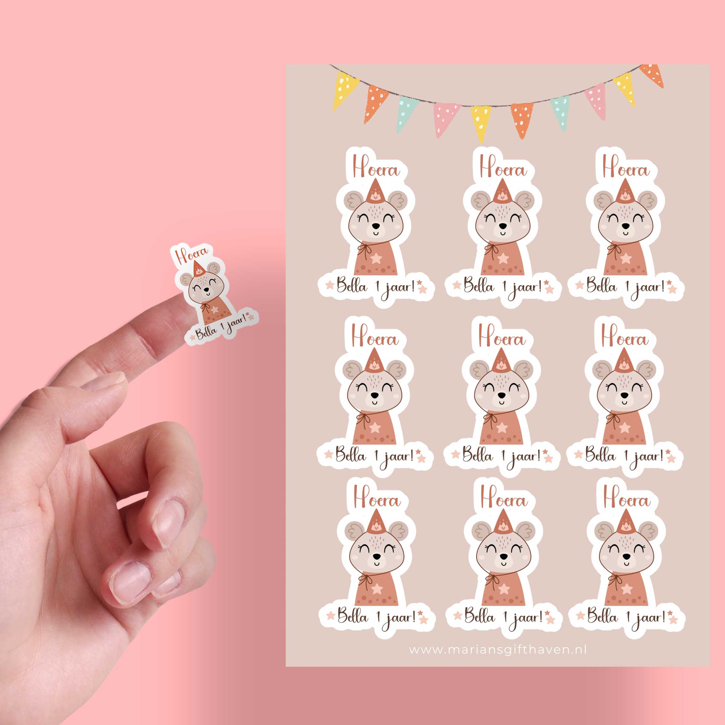 Hand houdt een muis-sticker vast met de tekst ‘Hoera Bella 1 jaar!’ naast een stickervel met 9 stickers