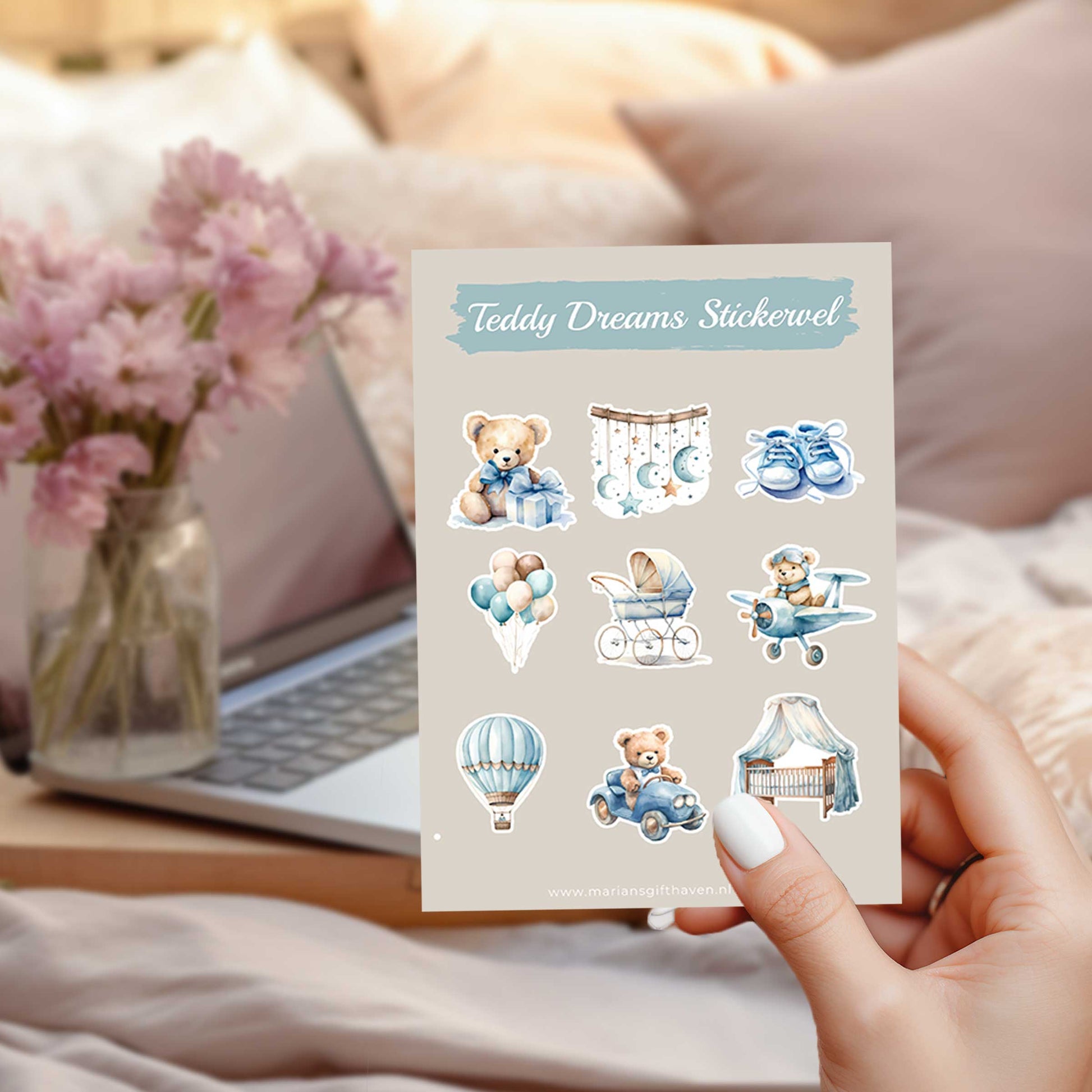 Teddy Dreams stickervel A6 met teddyberen, kinderwagen, luchtballon, babyschoentjes, wiegje en ballonnen in zachte blauw- en beigetinten, vastgehouden in een slaapkamer naast een laptop en roze bloemen.