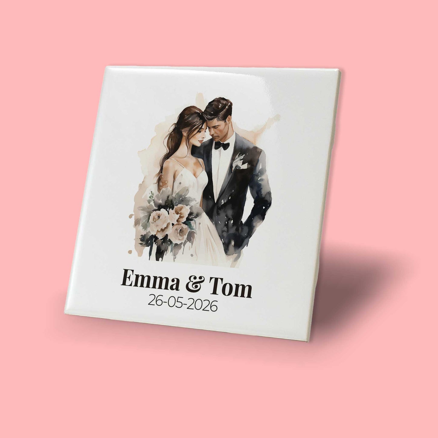 Schuin zijaanzicht van een keramisch trouwtegeltje met romantische illustratie van bruidspaar, namen en trouwdatum, weergegeven tegen een roze achtergrond.