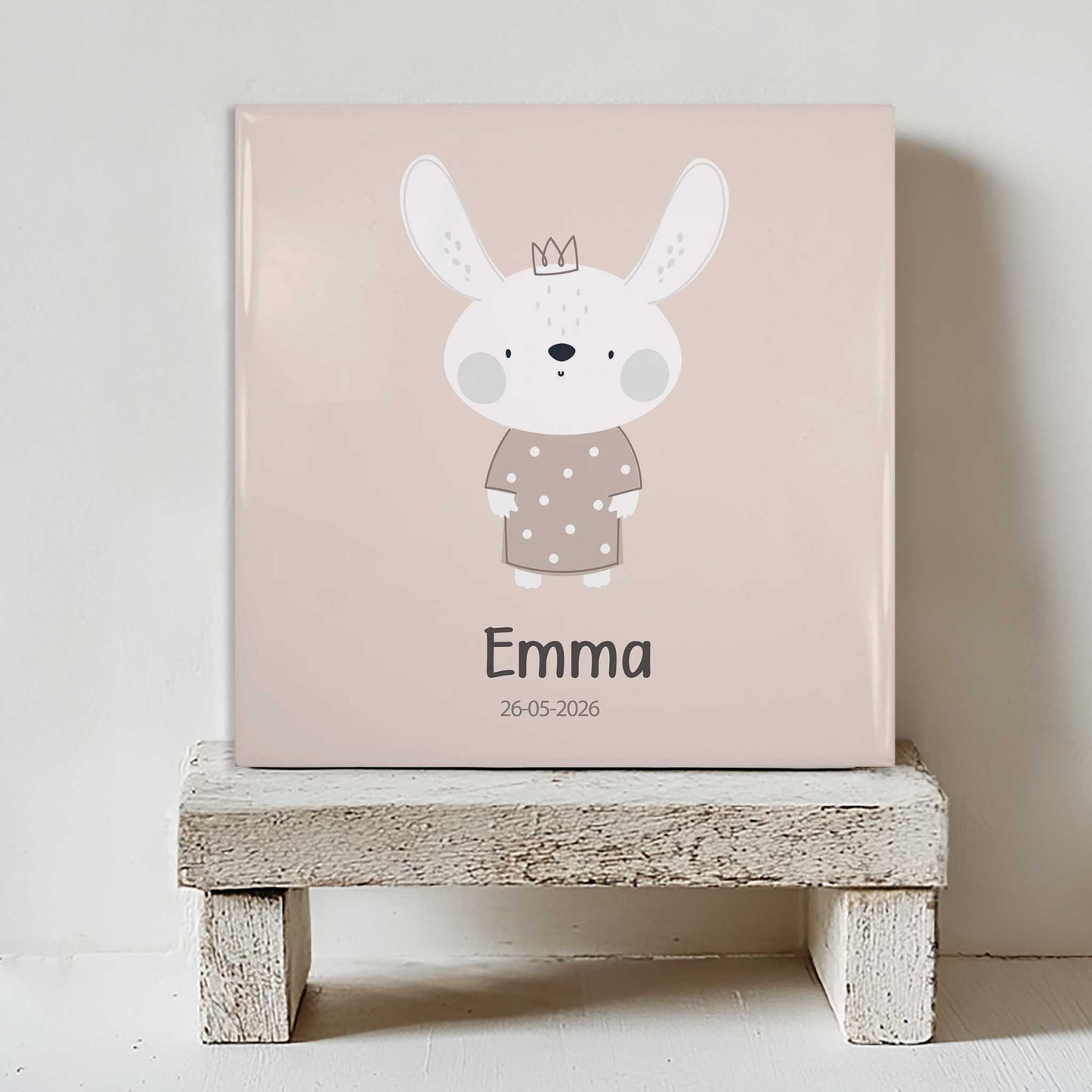 Gepersonaliseerd tegeltje met konijntje, naam Emma en geboortedatum op wit houten krukje tegen lichte muur