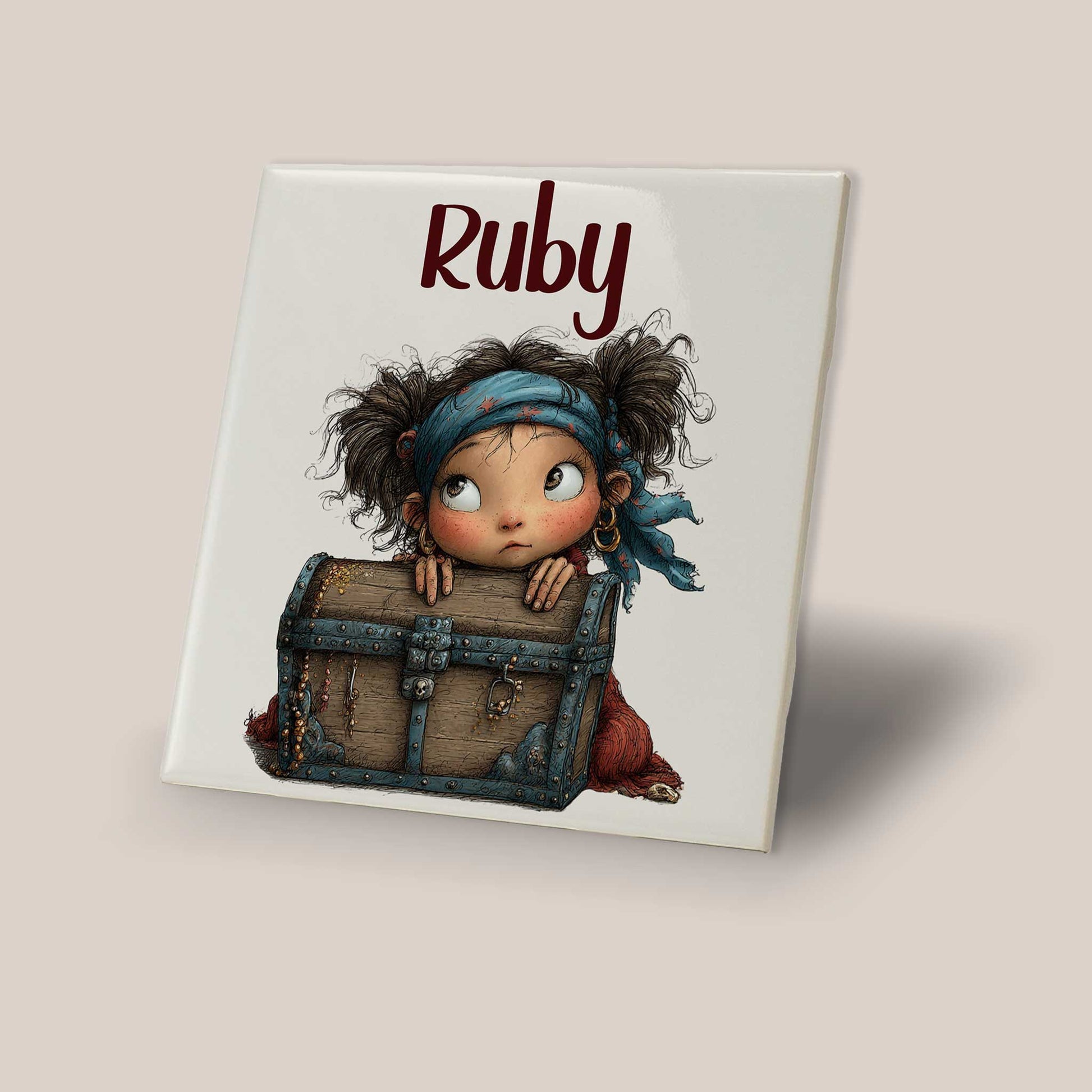 Keramisch tegeltje met de naam Ruby en een illustratie van een klein piratenmeisje achter een houten schatkist op een lichte achtergrond.