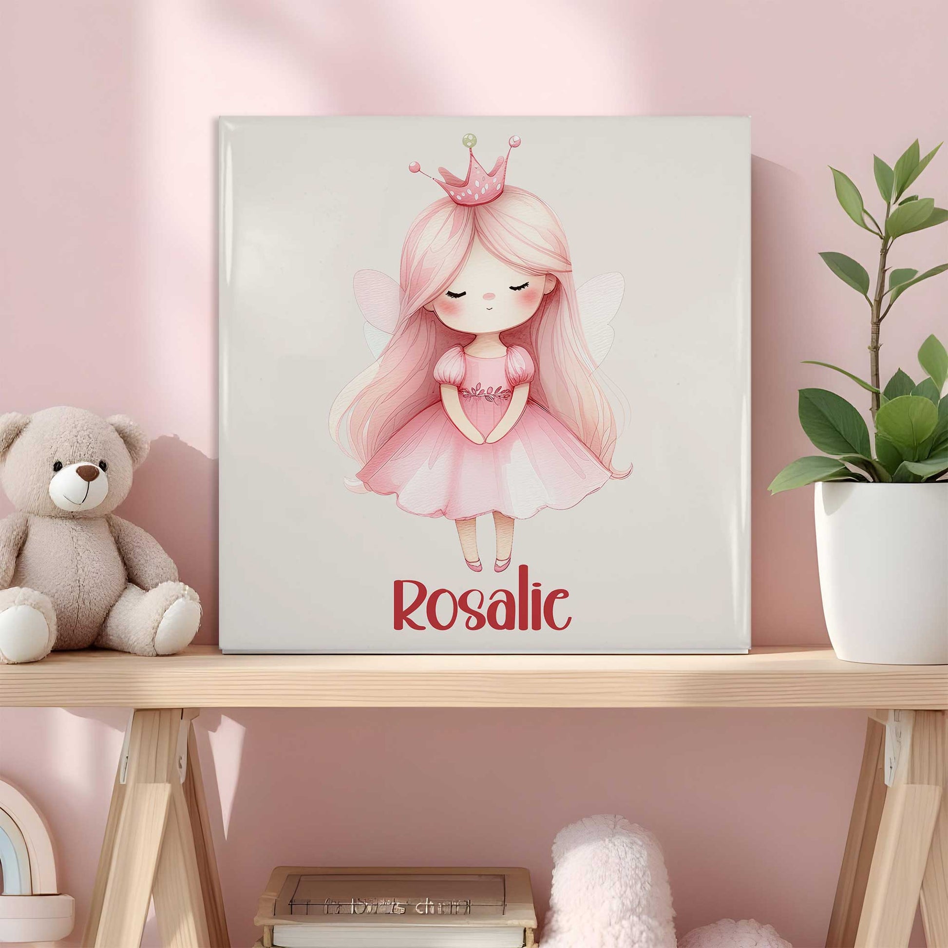 Keramisch tegeltje met een prinses met roze haar, een roze jurk en een kroontje. Onder de illustratie staat de naam Rosalie. Het tegeltje staat op een houten plank in een roze kinderkamer naast een knuffelbeer en een plant.