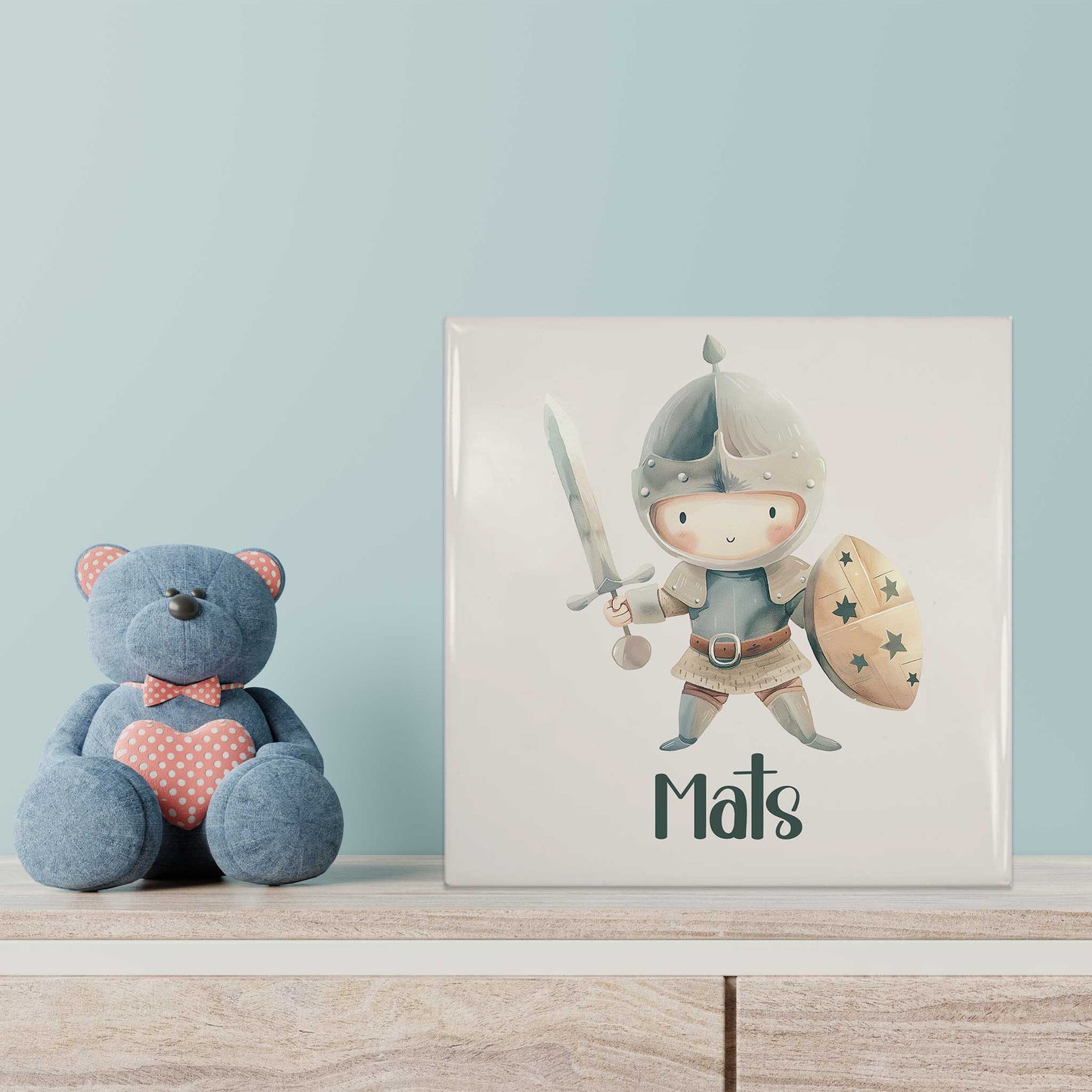 Keramisch riddertegeltje met naam Mats als decoratie op een kast in een kinderkamer naast een blauwe knuffelbeer.