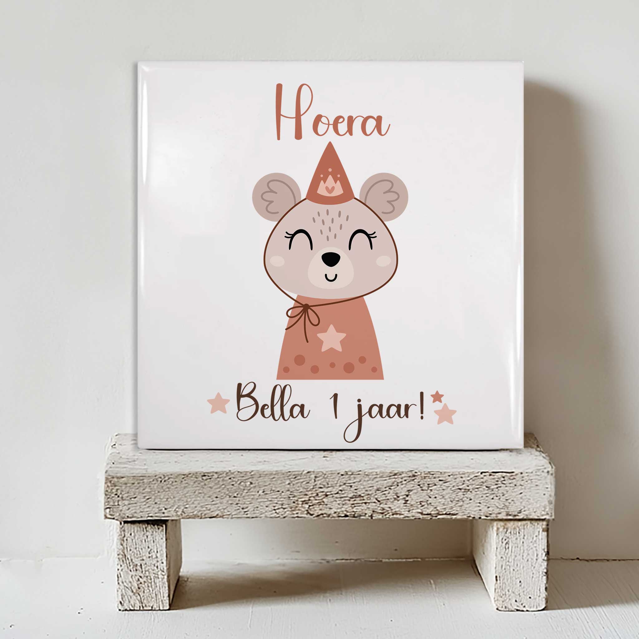 Keramisch tegeltje 15×15 cm met muis-illustratie en tekst ‘Hoera Bella 1 jaar!’ op een kleine witte houten standaard