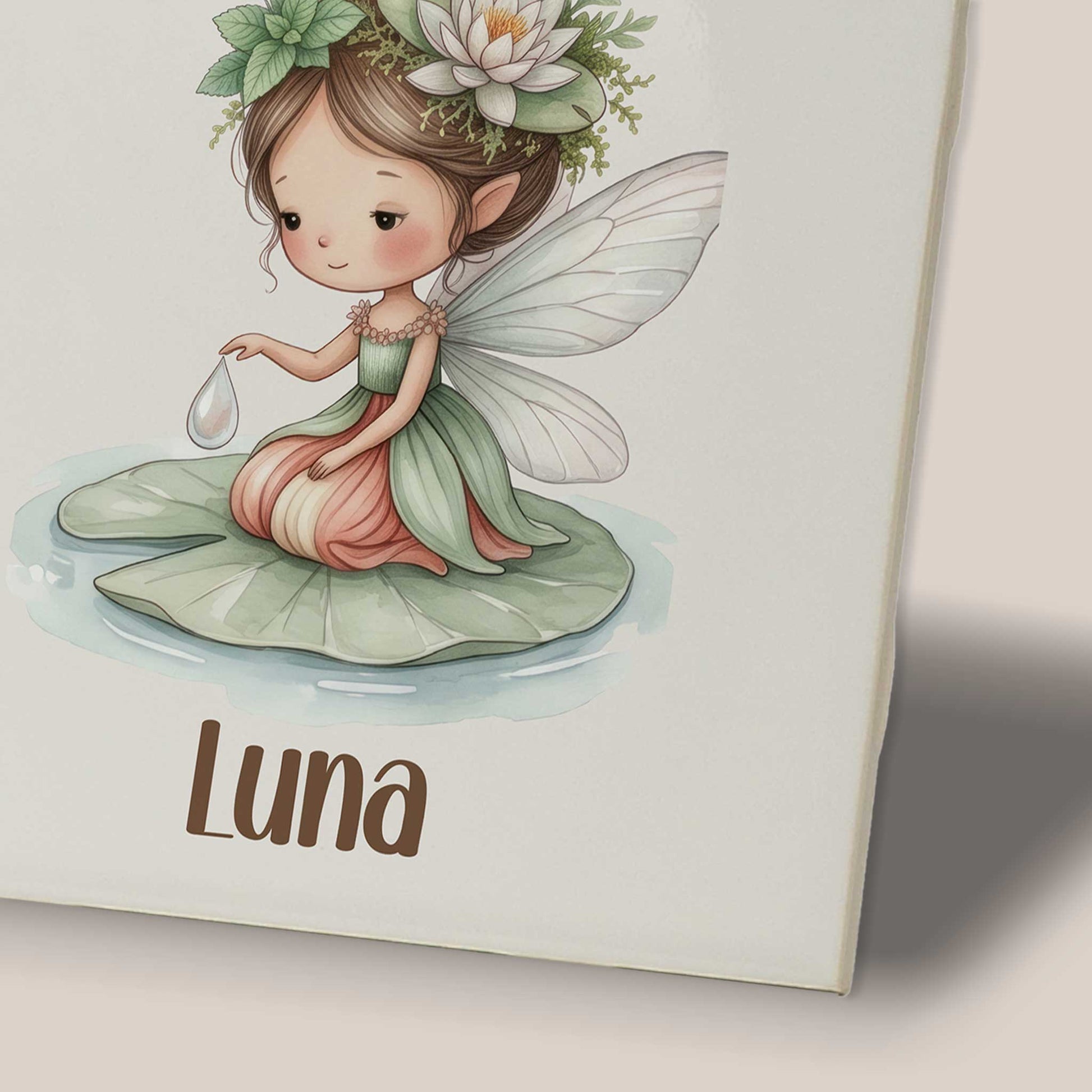 Close-up van een keramisch tegeltje met naam Luna en illustratie van een waterleliefee met bloemenkroon op een waterlelieblad.