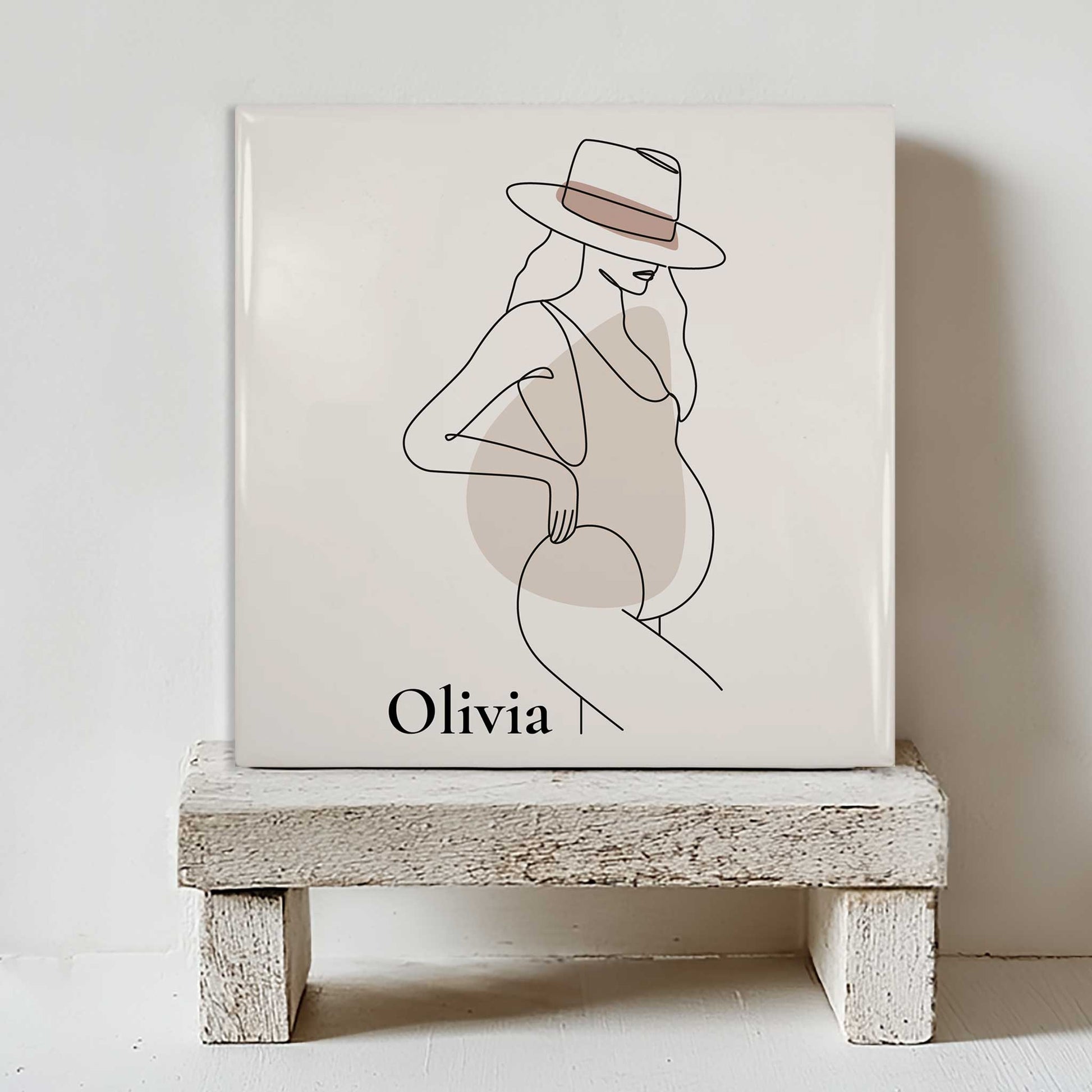 Minimalistisch zwangerschap tegeltje met lijntekening van zwangere vrouw en naam Olivia op wit houten krukje