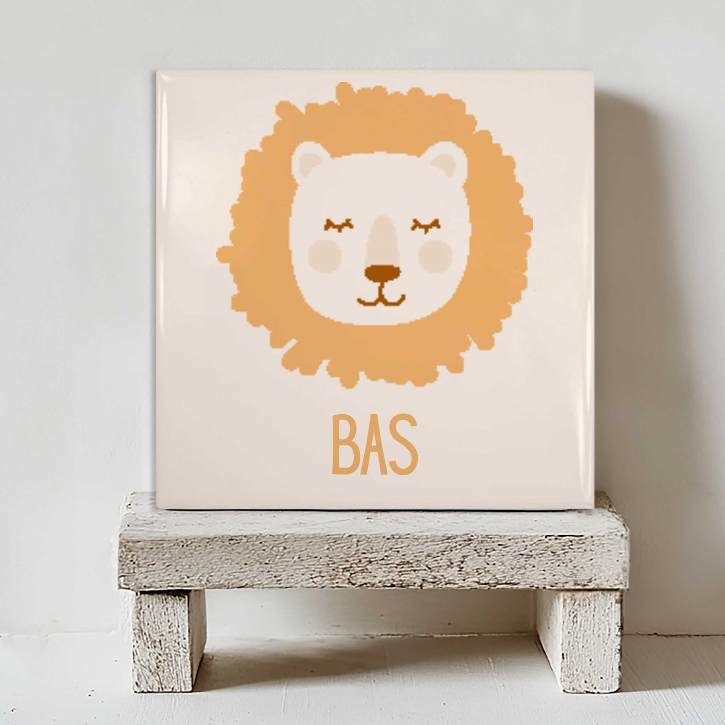 Wit keramisch tegeltje met leeuw en naam Bas, staand op een houten standaard