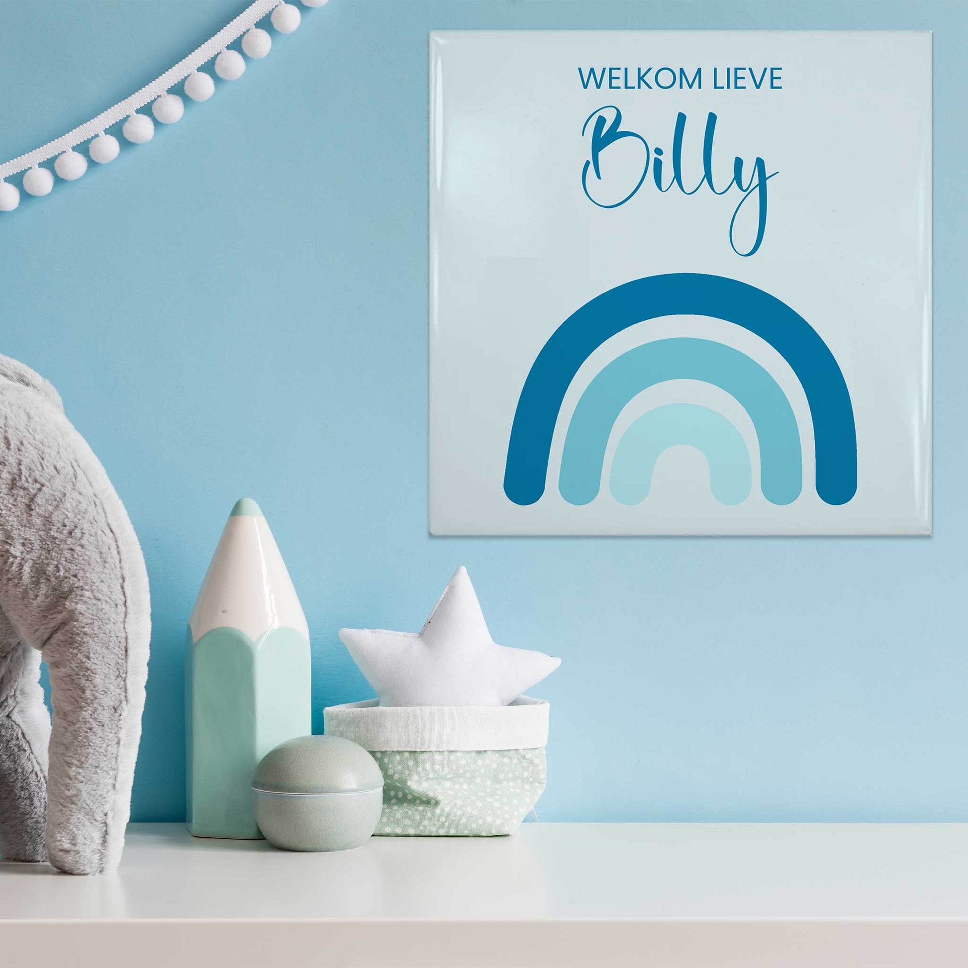 Babytegeltje met blauwe regenboog en naam Billy op blauwe muur tussen decoratie
