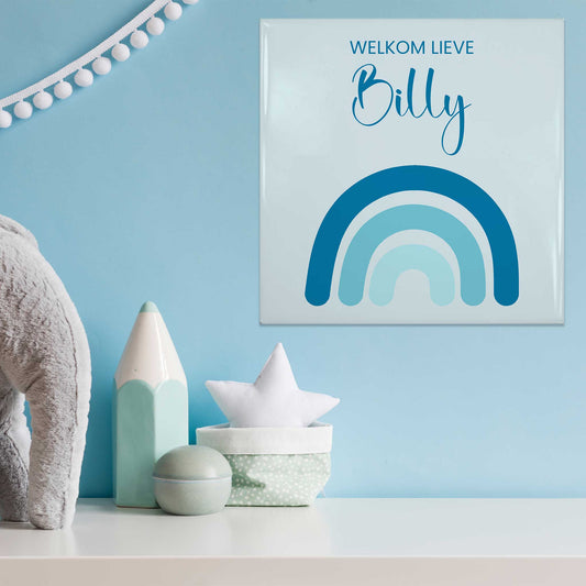 Babytegeltje met blauwe regenboog en naam Billy op blauwe muur tussen decoratie