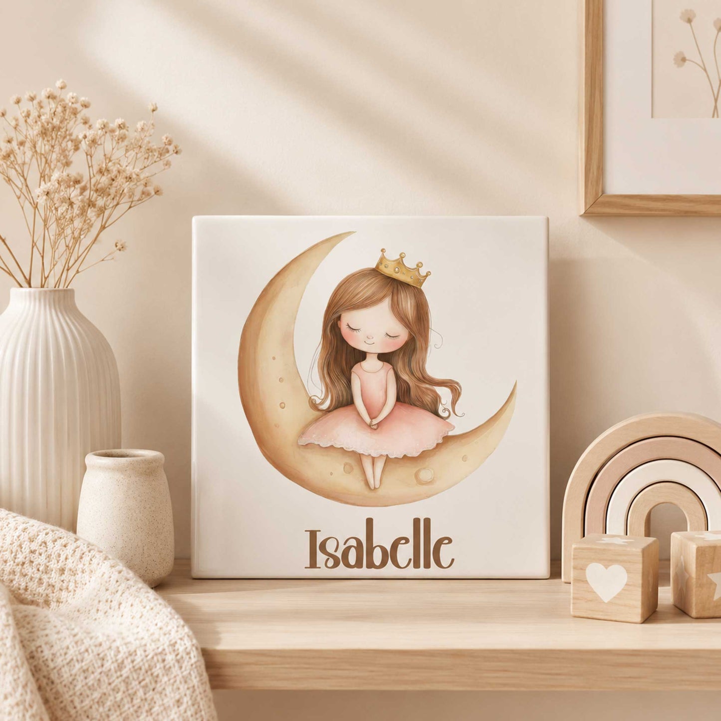 Keramisch prinsessen tegeltje met een prinses op een gouden maan en de naam Isabelle, geplaatst op een houten plank in een beige babykamer met droogbloemen en houten decoratie.