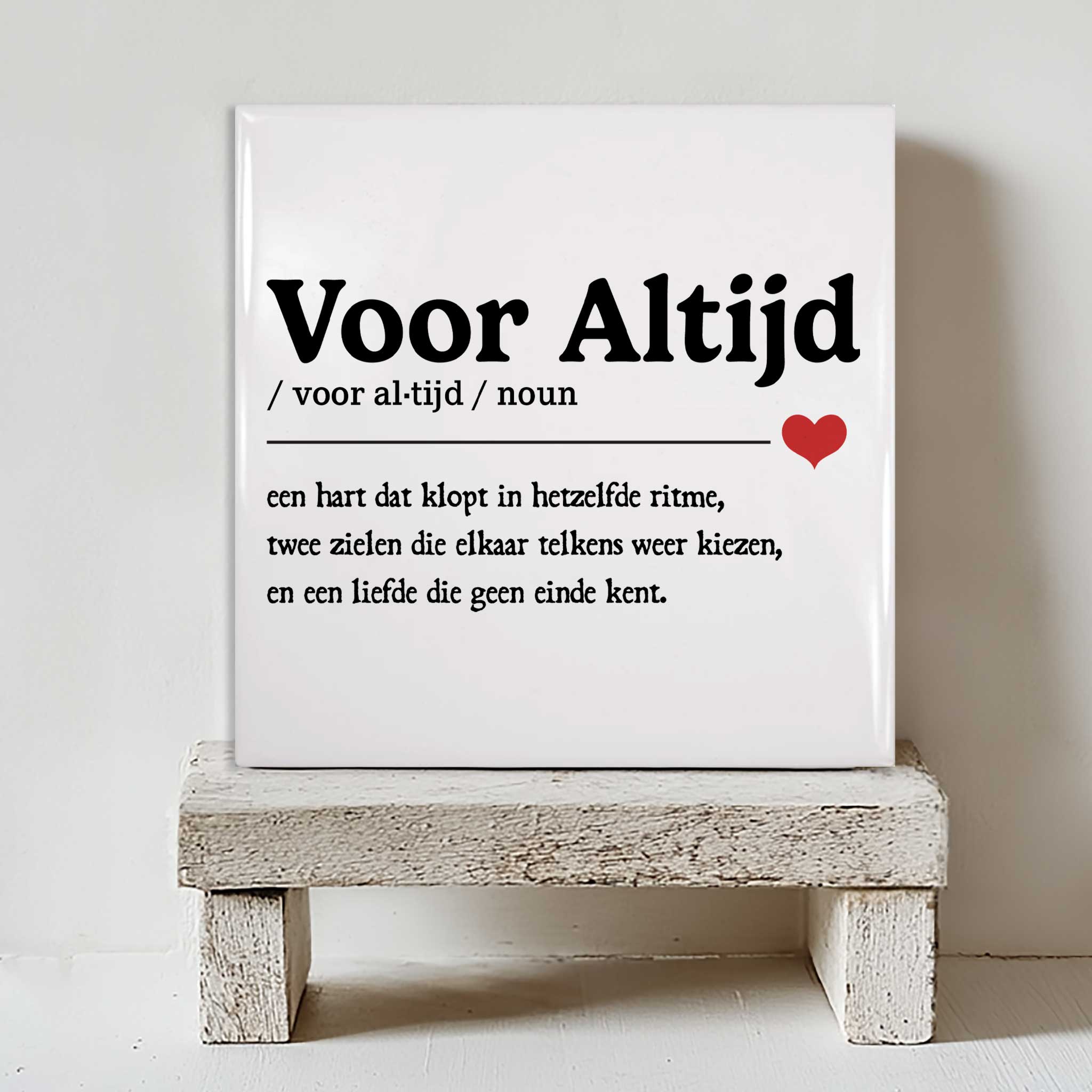 Keramisch tegeltje met de tekst “Voor Altijd” en een definitie over liefde, met een klein rood hartje, geplaatst op een witte houten kruk
