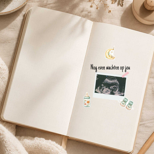 Open zwangerschapsdagboek met een echofoto, de tekst 'Nog even wachten op jou' en Tiny Dreams stickers van een maan, bloemenflesje en babyschoentjes op een beige pagina.