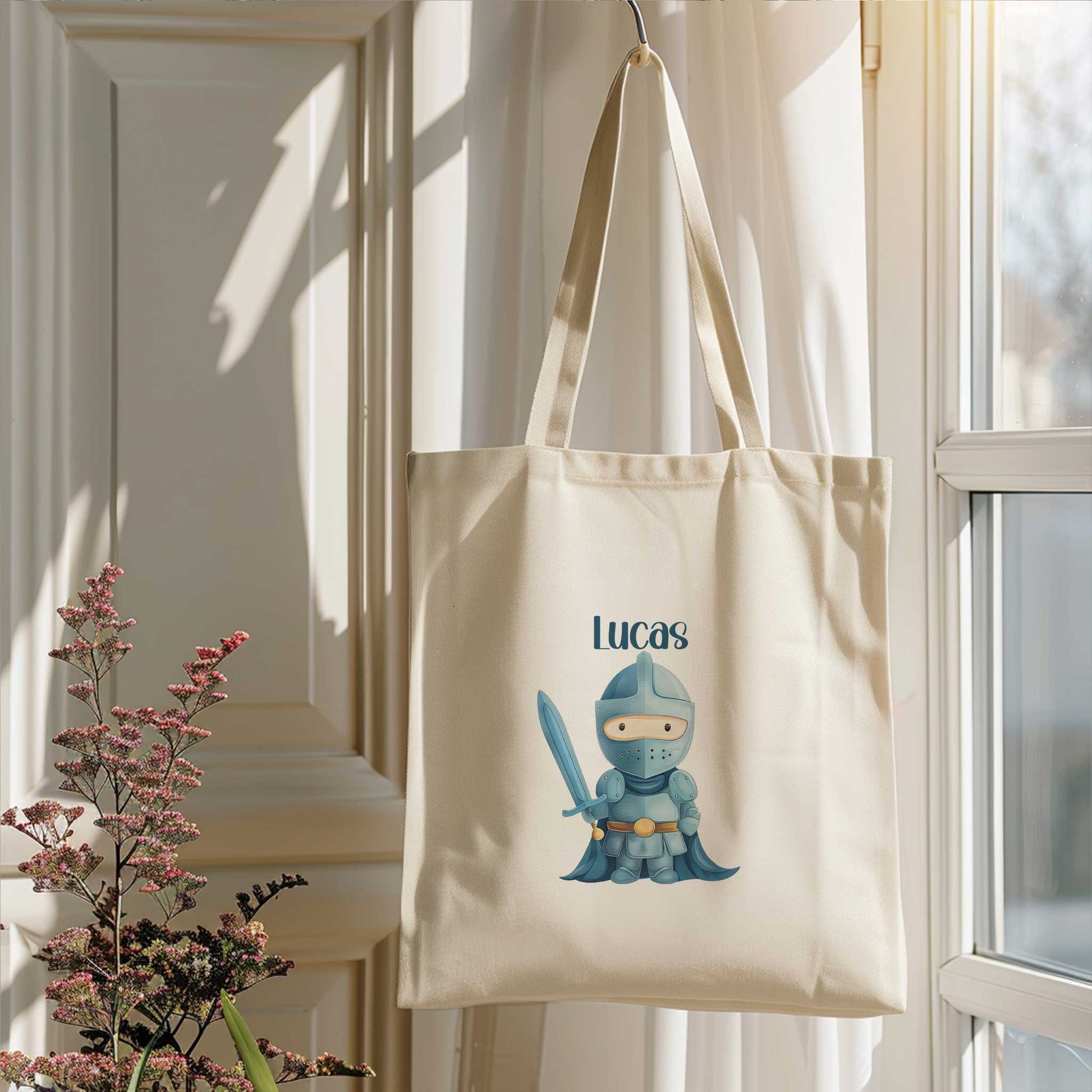 Naturel totebag met de naam Lucas en een illustratie van een blauwe ridder met een zwaard, hangend naast een raam.