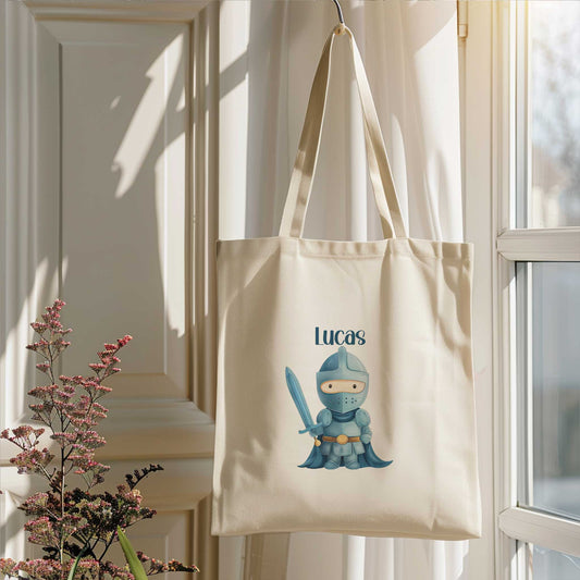 Naturel totebag met de naam Lucas en een illustratie van een blauwe ridder met een zwaard, hangend naast een raam.