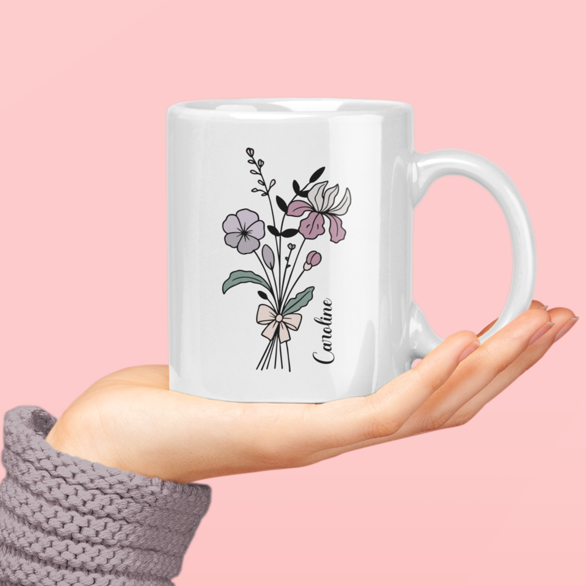 vrouw met op haar hand een gepersonaliseerde witte mok met lijnbloemen in paars roze tinten en een sierlijke naam in het zwart