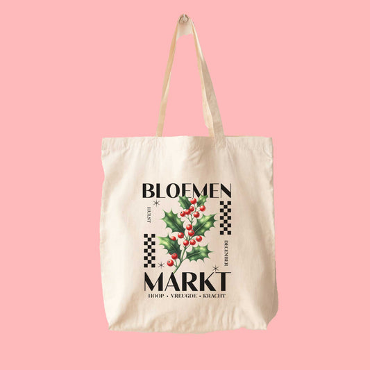 totebag met  de tekst bloemenmarkt en een illustratie van een geboortebloem van de maand december, hulst. Met onderaan de kernwoorden van deze maand : hoop, vreugde, kracht.