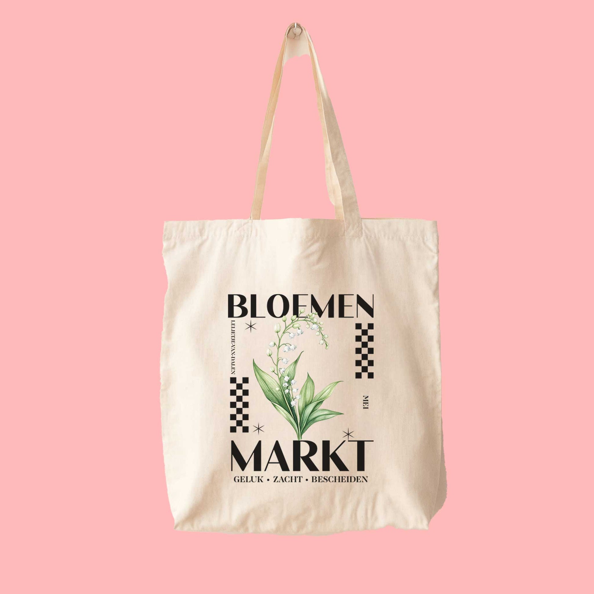 totebag met  de tekst bloemenmarkt en een illustratie van een geboortebloem van de maand mei, een Lelietje-van-dalen. Met onderaan de kernwoorden van deze maand : geluk,zacht,bescheiden.
