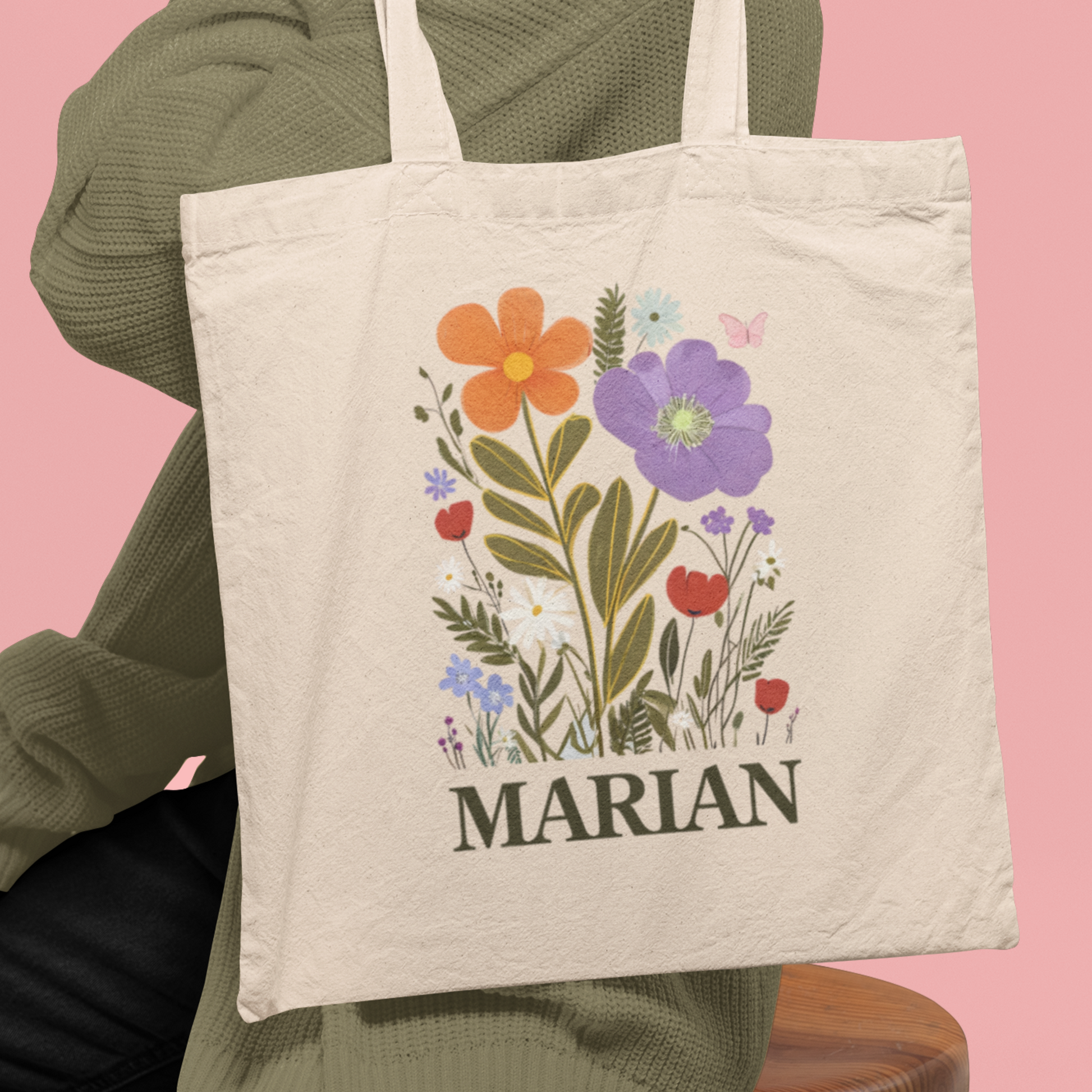 vrouw met een Naturelkleurige totebag met bloemenillustratie in zachte tinten en gepersonaliseerde naam in donkergroen. Botanische en boho stijl om haar schouder