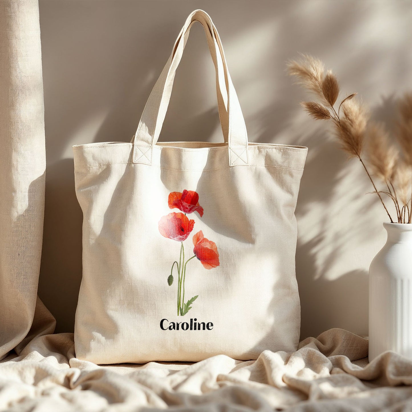 Gepersonaliseerde totebag met klaprozen en naam  op een naturel deken tegen een beige muur