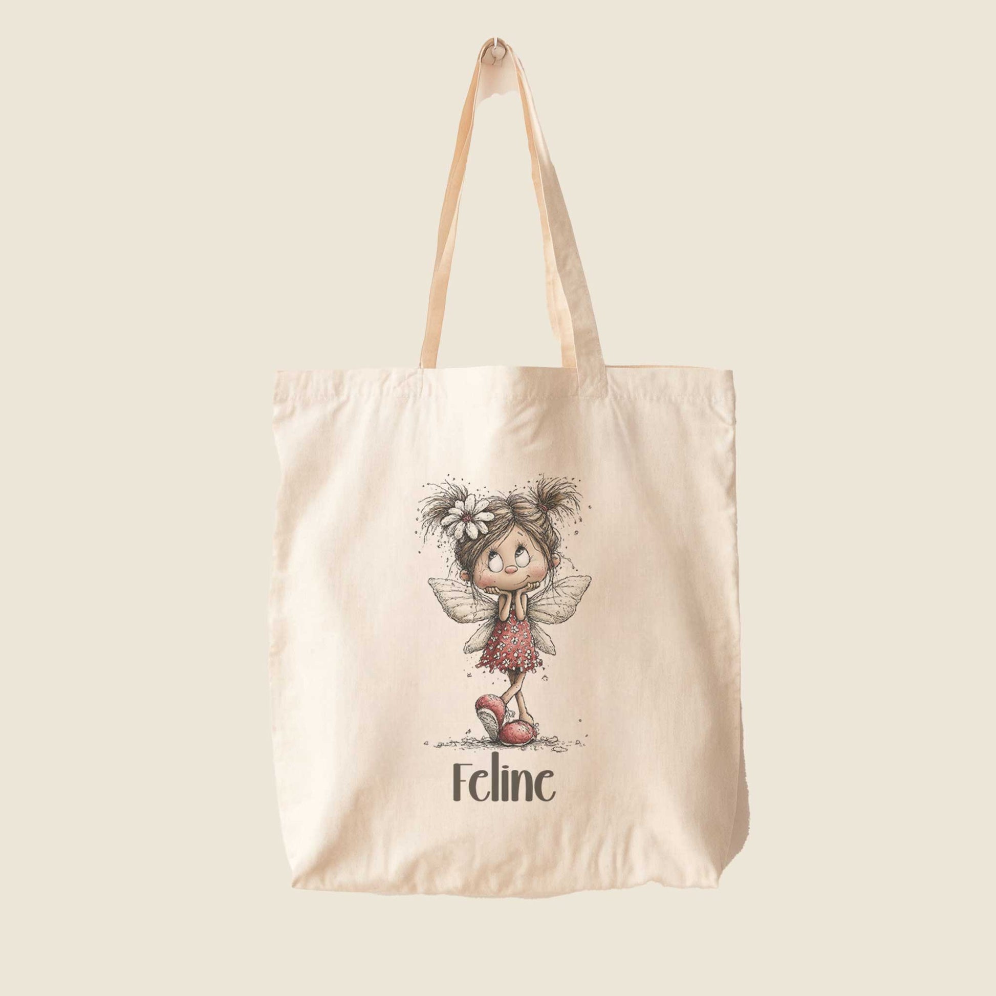 Beige totebag op een lichte achtergrond met een illustratie van een fee in een rode jurk en de naam Feline.