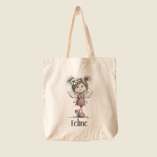 Beige totebag op een lichte achtergrond met een illustratie van een fee in een rode jurk en de naam Feline.
