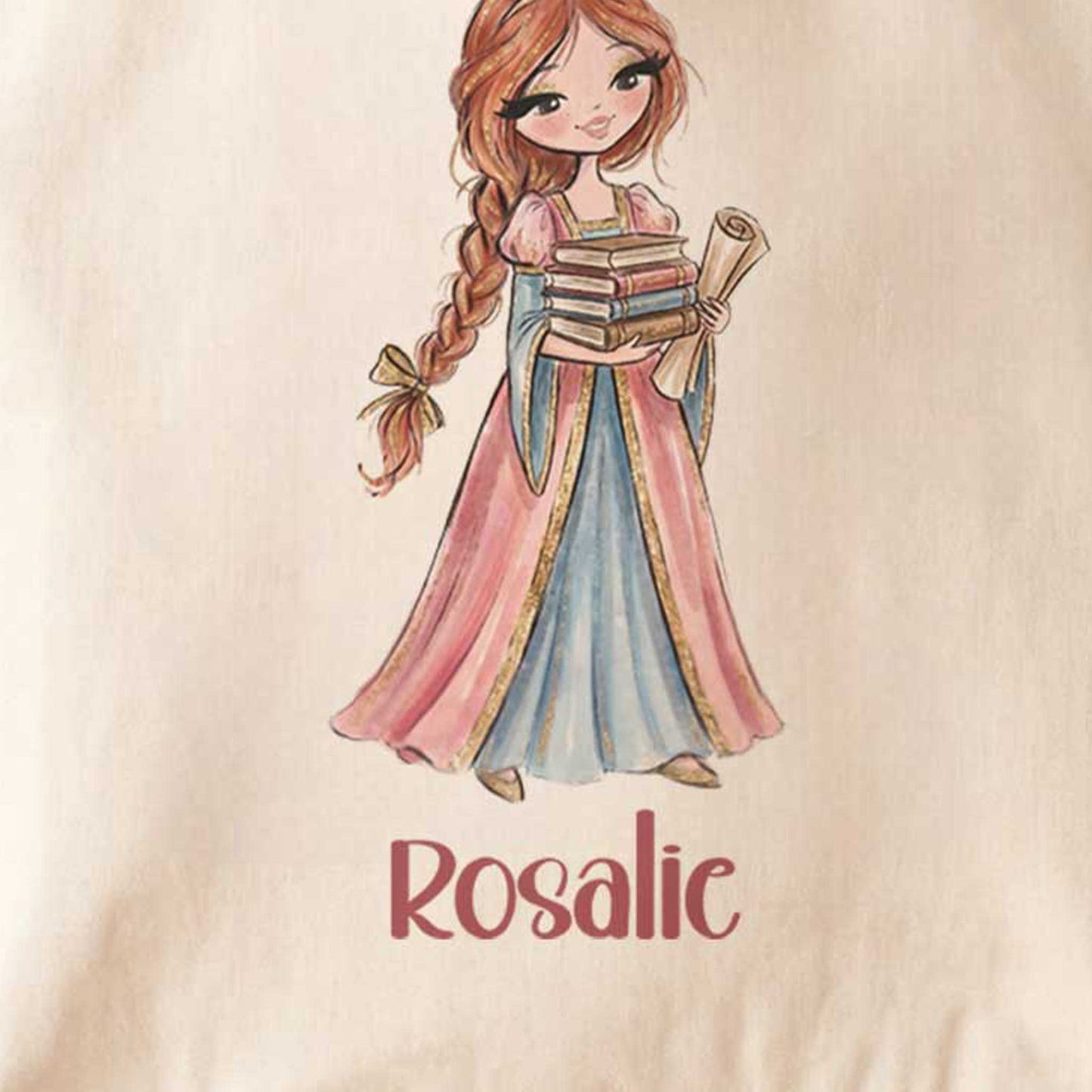 Close-up van een beige totebag met een prinses in een roze en blauwe jurk die een stapel boeken en een opgerolde perkamentrol vasthoudt. Onder de illustratie staat de naam Rosalie.