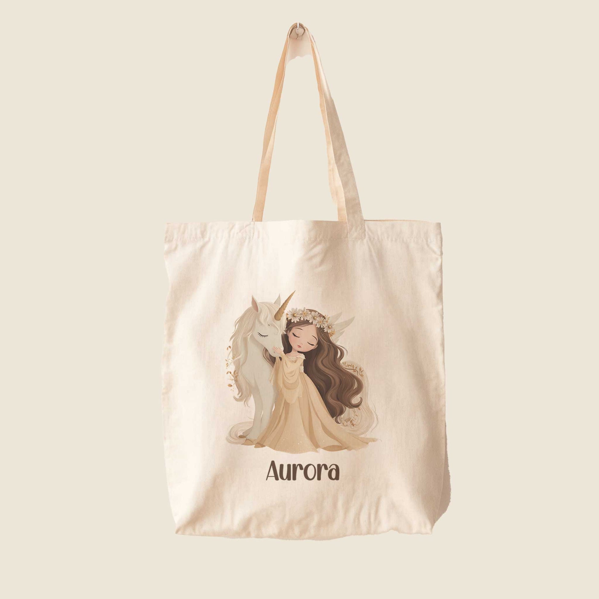 Beige totebag met een illustratie van een prinses die een witte eenhoorn knuffelt en de naam Aurora op een effen lichte achtergrond.