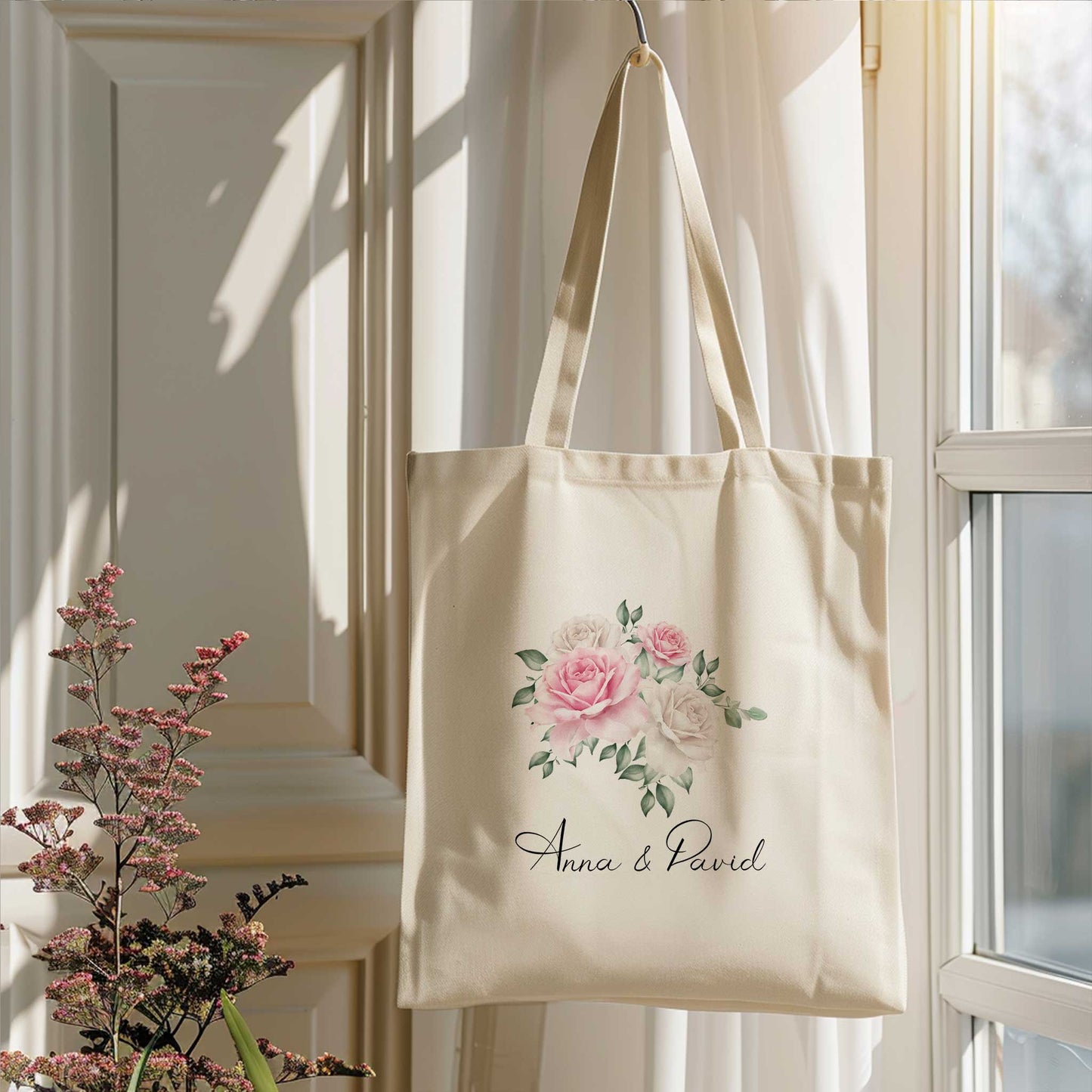 close up van Tote bag met roze en witte rozenillustratie en namen Anna & David, voor een raam