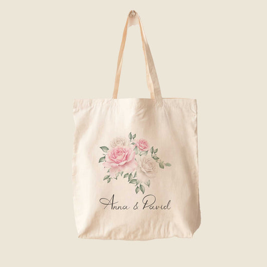 Tote bag met roze en witte rozenillustratie en namen Anna & David, op effen beige achtergrond