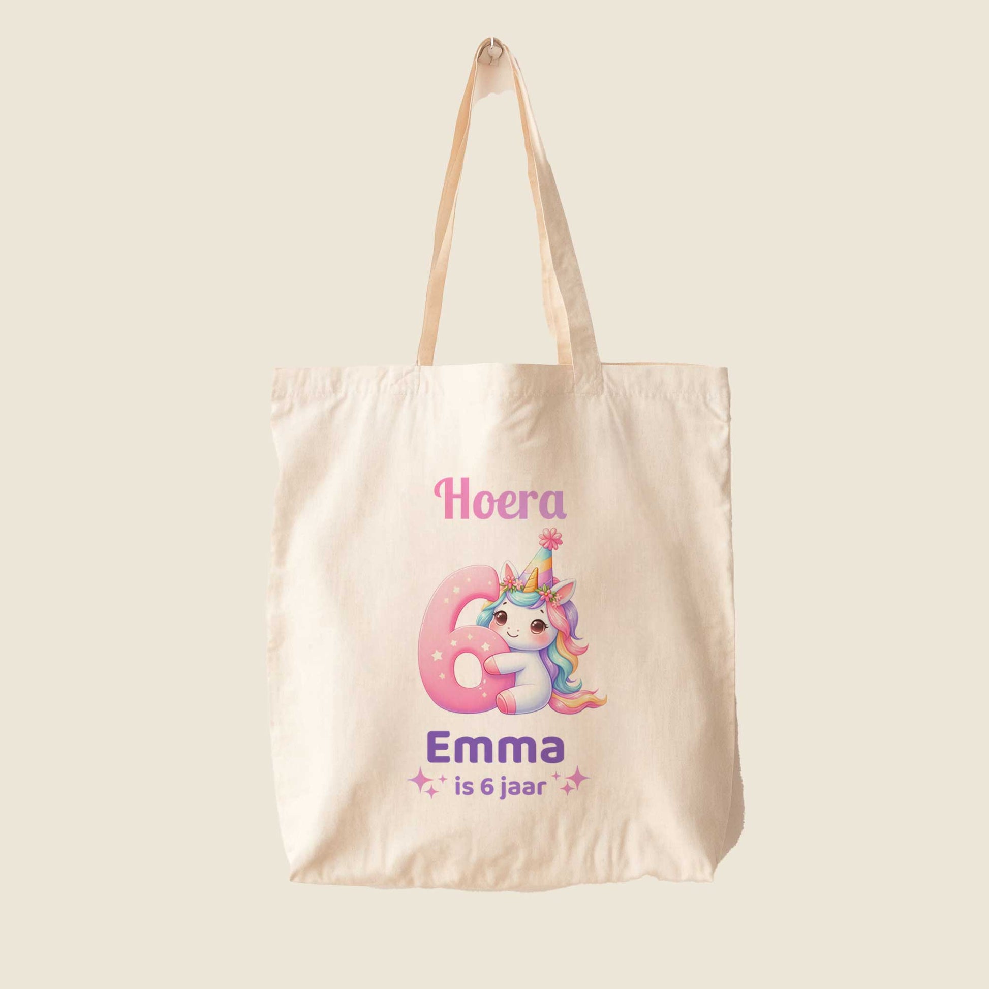 Lichte totebag op een effen achtergrond met een unicorn, een groot roze cijfer 6 en de tekst Hoera Emma is 6 jaar.