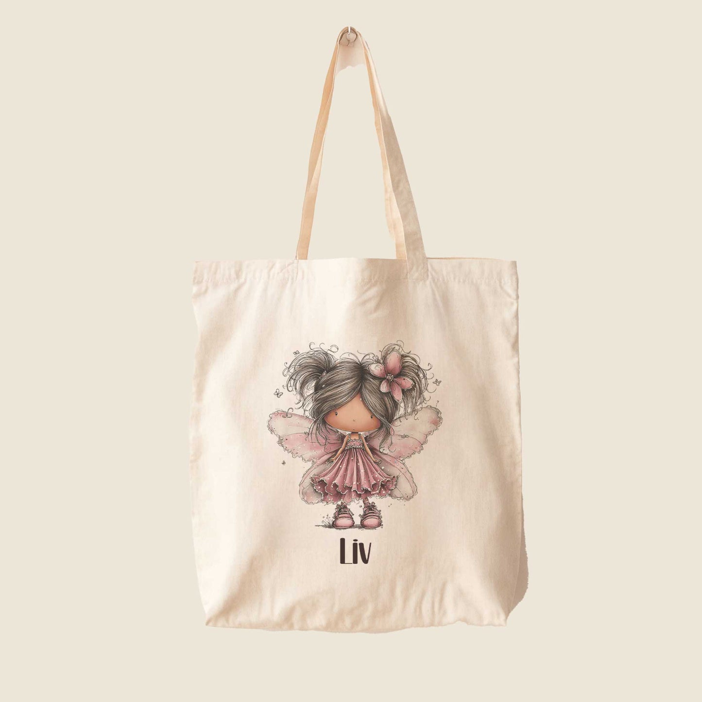 Beige totebag op een lichte achtergrond met een illustratie van een fee met roze vleugels en de naam Liv.