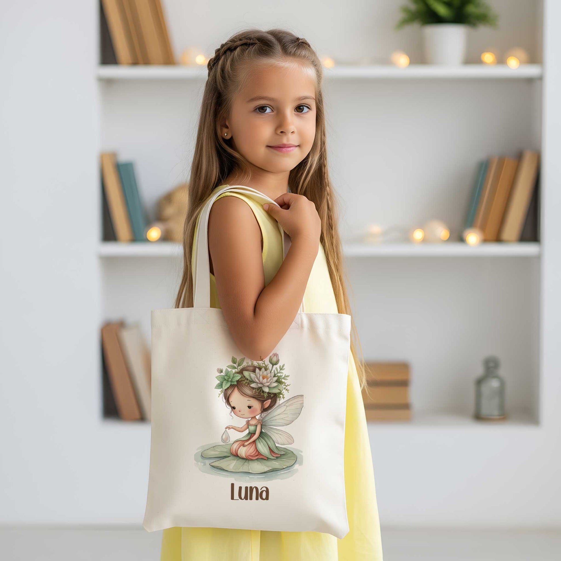 Meisje met een beige totebag over haar schouder, met daarop een illustratie van een fee op een waterlelieblad en de naam Luna.
