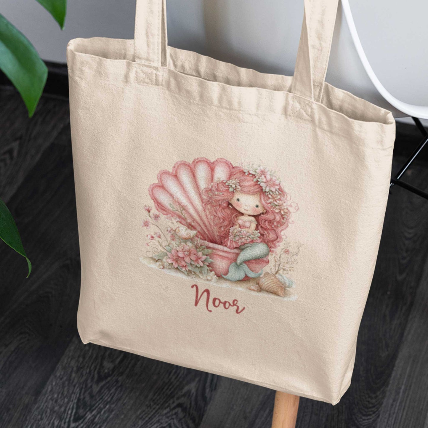 Katoenen totebag met gepersonaliseerde naam Noor. Op de tas staat een roze zeemeermin met lang krullend haar die in een grote geopende roze schelp zit, omringd door bloemen, schelpen en zachte pastelkleuren.