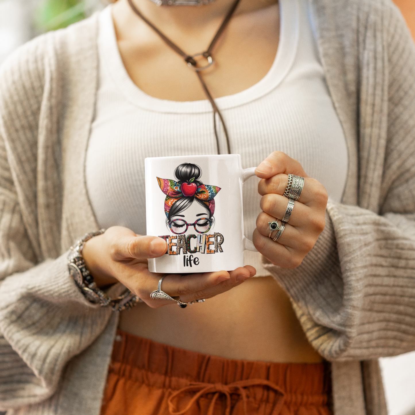 vrouw met mok in haar handen waarop teacher life staat en een illustratie van een vrouw met bril en haarband in bruin rode tinten